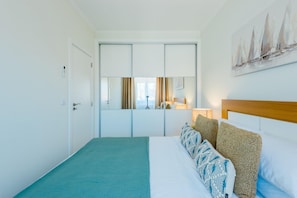 Ein Hotelzimmer mit Bett, Spiegel, Gemälde und Tür.