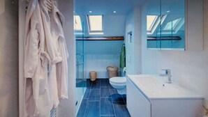 Une salle de bain moderne avec une lucarne, une baignoire blanche et un grand miroir.