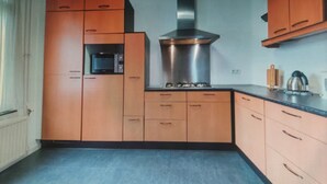 Une cuisine avec des armoires en bois, une hotte de cuisinière en acier inoxydable et un four à micro-ondes.