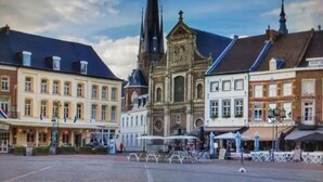 Un bâtiment historique doté d’une tour imposante et d’une vaste place publique avec des espaces de repos en plein air.