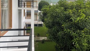 Un apartamento moderno con balcón, vistas a un jardín arbolado y una torre de agua al fondo.