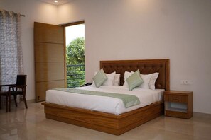 A bedroom with a large bed, wooden headboard, and a nightstand. - THE WHITE OAK CORBETT SPA & RESORT (Ramnagar)