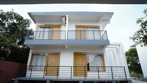 Un edificio moderno de dos plantas con balcones, ventanas amplias y techo plano.
