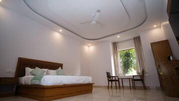 A bedroom with a wooden bed, a ceiling fan, a window with curtains, and a small table with chairs.