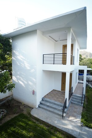 A modern two-story house with a balcony, a staircase, and a small garden area. - THE WHITE OAK CORBETT SPA & RESORT (Ramnagar)