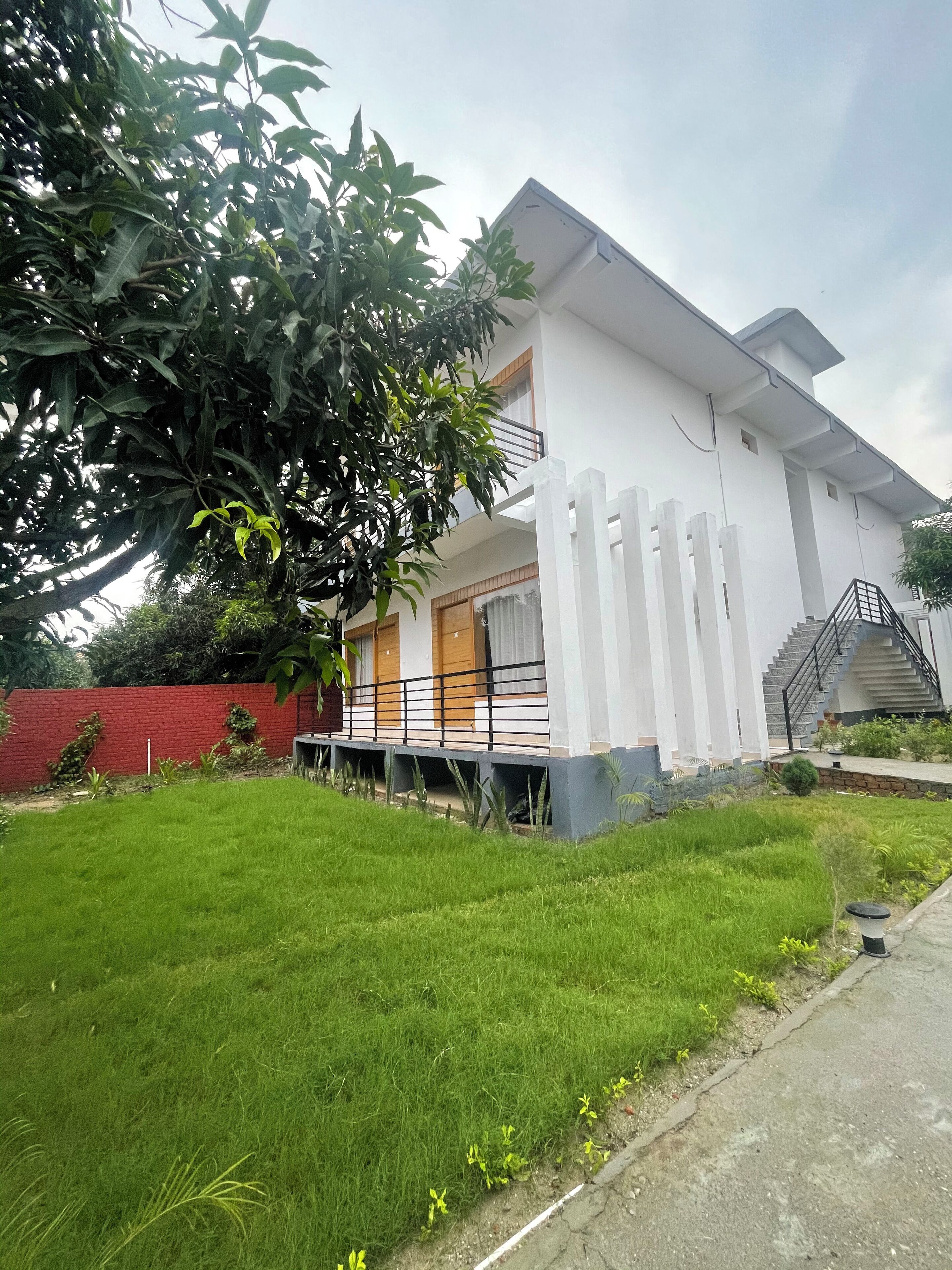 A modern two-story house with a white exterior, a covered porch, and a staircase leading to the upper floor.