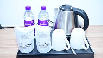Een dienblad met Bailey waterflessen, een waterkoker en twee glazen zakken met de tekst 'The Dwelling'.