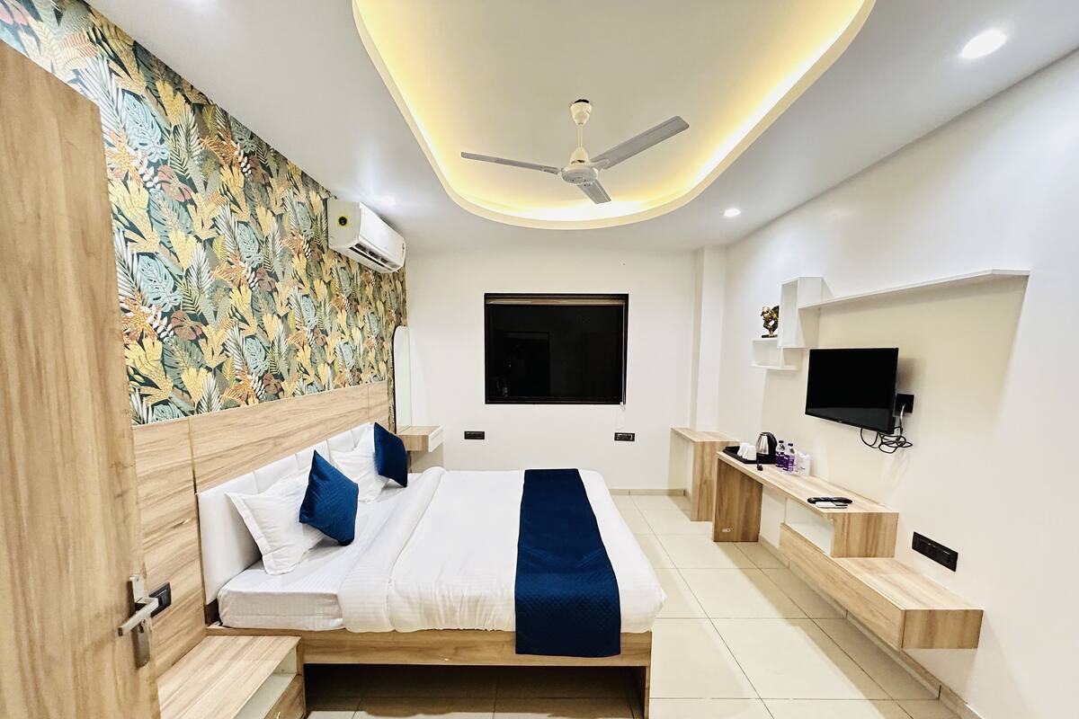 A modern bedroom with a bed, a ceiling fan, a TV, and a wall-mounted shelf.