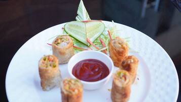 Un plato de rollitos de primavera con kétchup y rodajas de pepino.