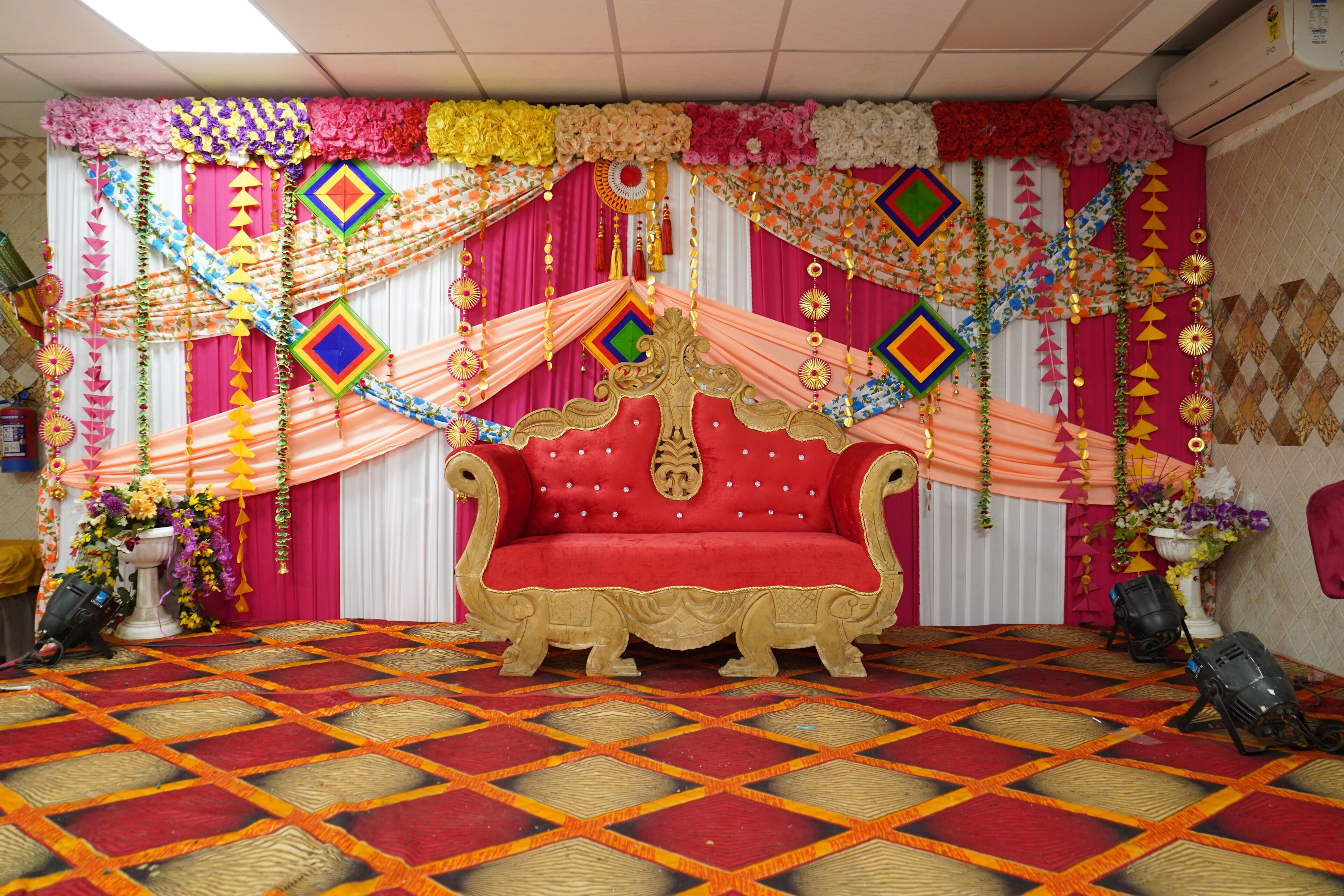 A stage with a red sofa, colorful drapes, and a patterned carpet.