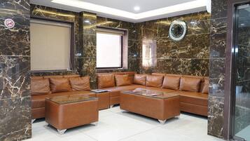 Una sala de estar moderna con un sofá seccional de cuero marrón, una mesa de centro de vidrio y un ventanal grande.