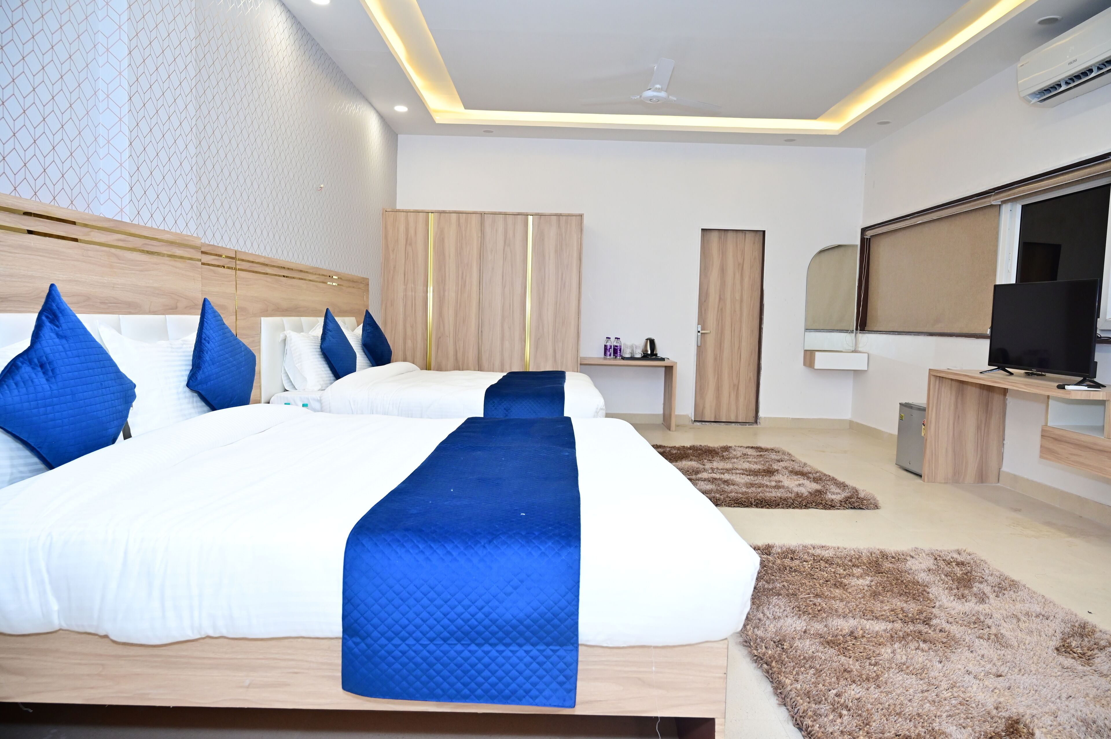 Ein modernes Hotelzimmer mit einem großen Bett, zwei Nachttischen, einem Fernseher und einem Kleiderschrank.
