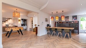 A modern kitchen with a herringbone floor pattern, a central island with bar stools, pendant lighting, and a view of the outdoors. - La clarté - wonderful refurbish home with garden and pool (Champagne-au-Mont-d'Or)