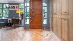 A room with a herringbone wooden floor, a wooden door, and a view of greenery through large windows. - La clarté - wonderful refurbish home with garden and pool (Champagne-au-Mont-d'Or)