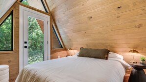 Ein Schlafzimmer mit einem großen Bett, einem Fenster und einer Tür, die zu einem Außenbereich führt.