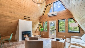Ein gemütliches Loft mit Kamin, Holzwänden, großen Fenstern und einer modernen Sitzecke.