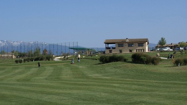 A golf course with a house in the background, a clear sky, and mountains in the distance. - Chalet en Grajera (Grajera)