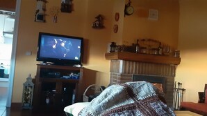 A living room with a television, fireplace, and various wall decorations. - Chalet en Grajera (Grajera)