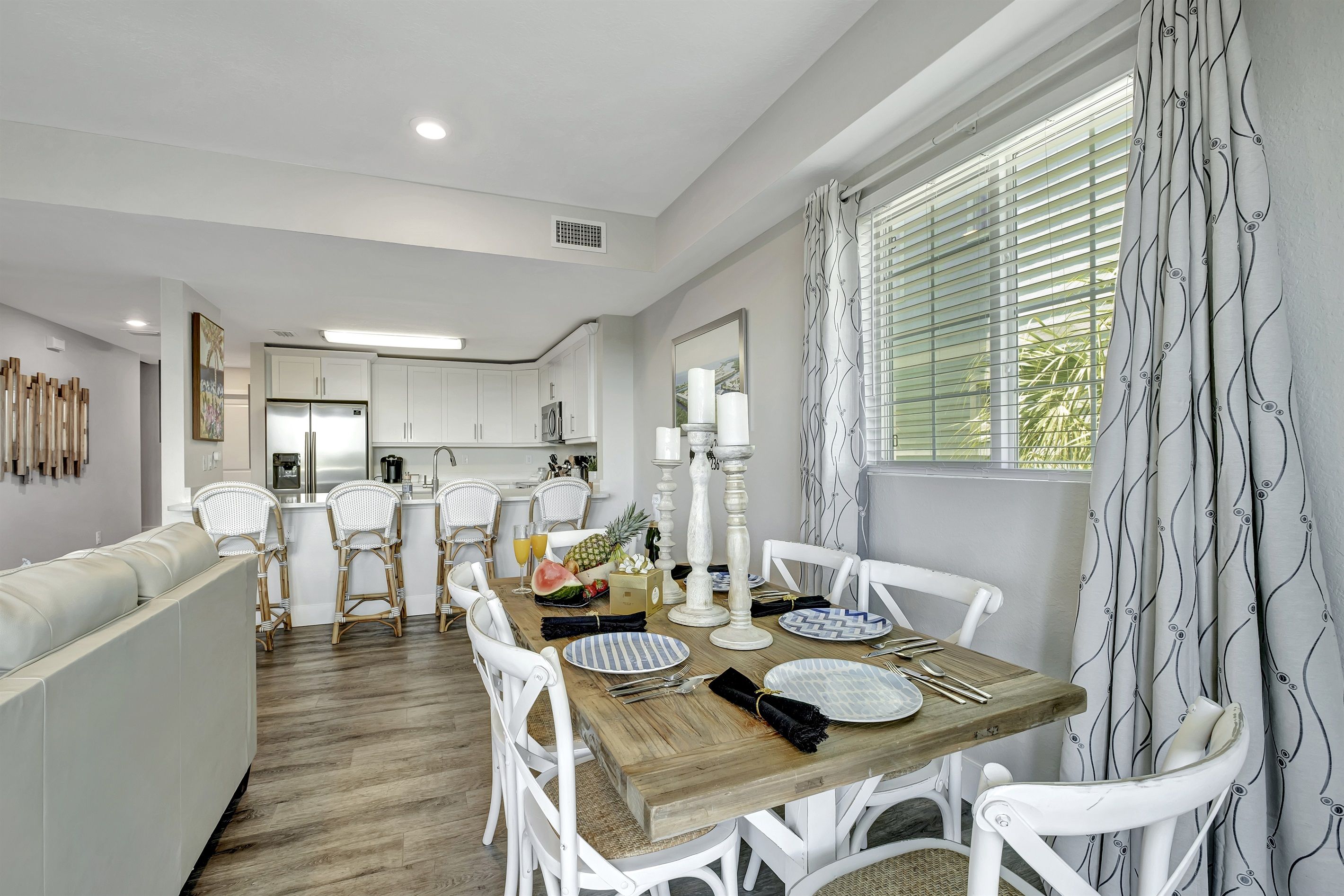 A modern kitchen with white cabinetry and a dining area with a wooden table set for four.