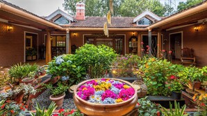 A courtyard with a large flower arrangement, potted plants, and a brick building with a tiled roof.