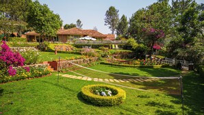 A well-maintained garden with a variety of plants and flowers, a neatly trimmed lawn, and a small circular hedge in the foreground.