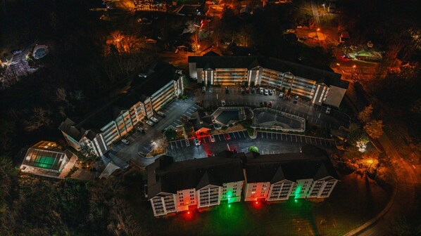 An aerial view of a hotel with multiple buildings, parking areas, and a landscaped courtyard.