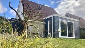 A modern house with a sloped roof, a stone foundation, and a large sliding glass door.