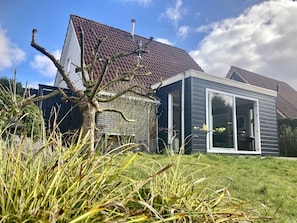 A modern house with a sloped roof, a stone foundation, and a large sliding glass door.