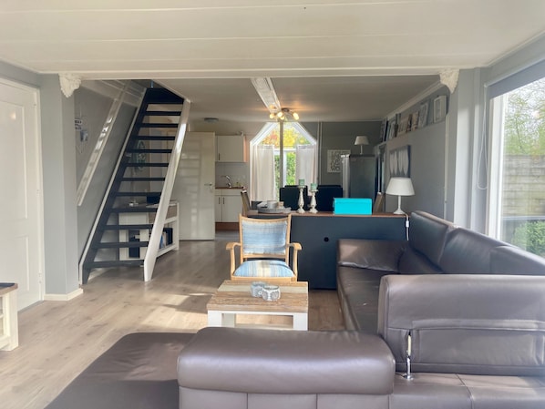 A modern living room with a sofa, a coffee table, and a staircase leading to a kitchen.