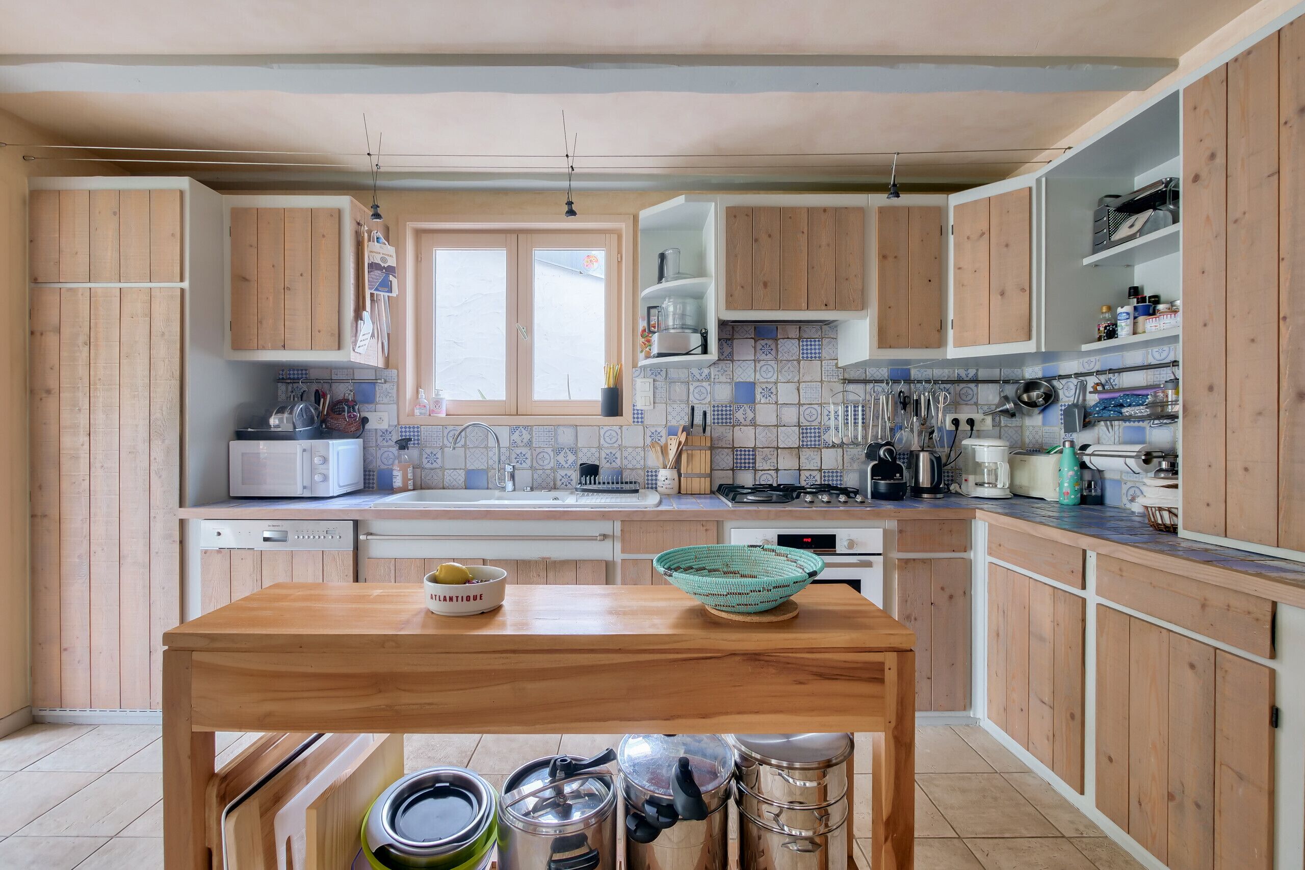 Una cocina con armarios de madera, microondas, lavamanos y una mesa de comedor.
