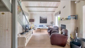 Una sala de estar moderna con piso de madera, un juego de sofá, una televisión y una chimenea.