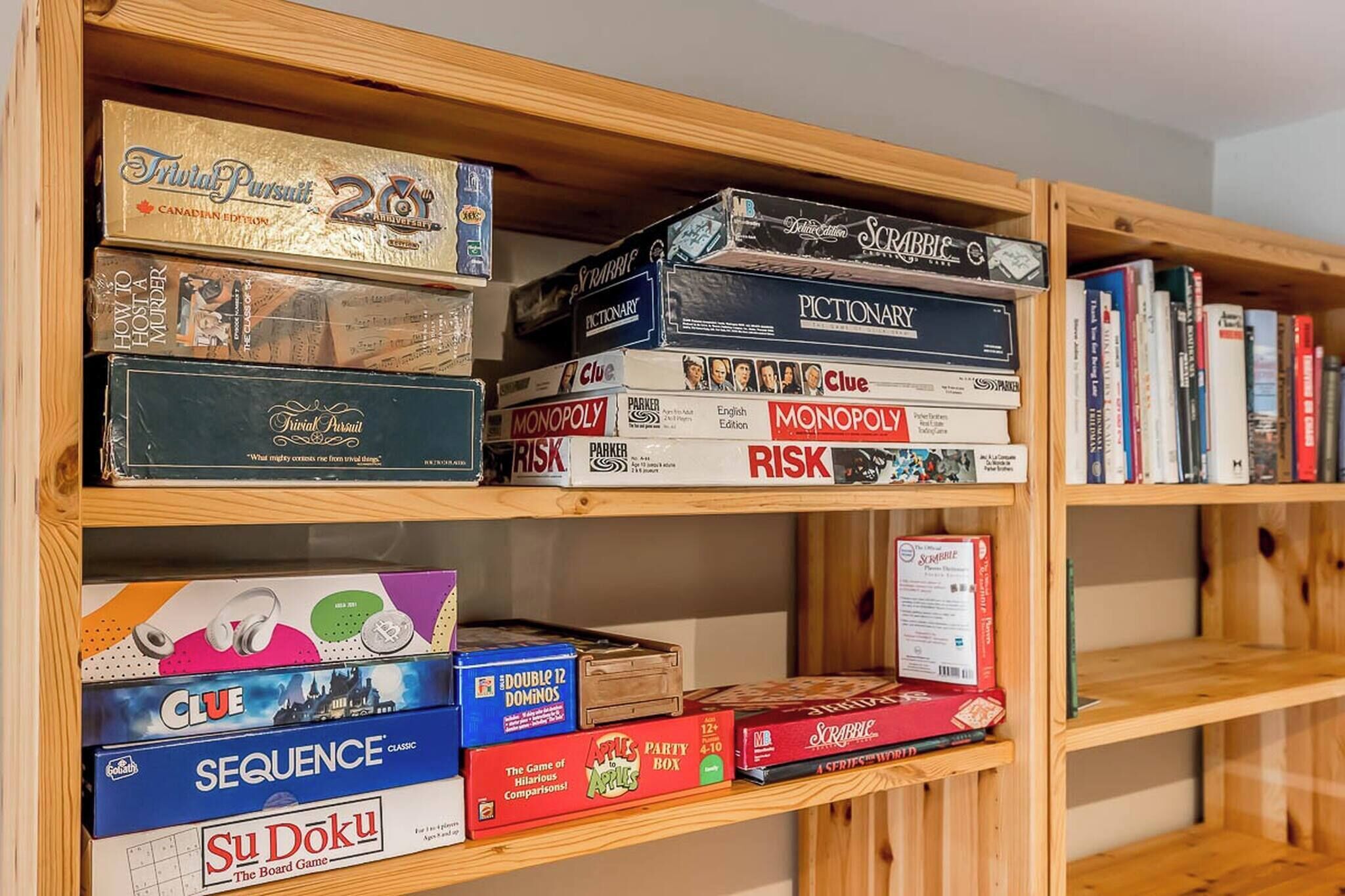 A bookshelf with various board games, including Trivia Pursuit, Monopoly, Clue, and Scrabble.