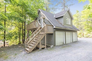 A two-story house with a wooden staircase leading to a deck, surrounded by trees. - Muskoka Lakeshore Cottage Bliss (Gravenhurst)