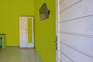 Un pasillo con una pared verde, una puerta blanca y una pequeña mesa.