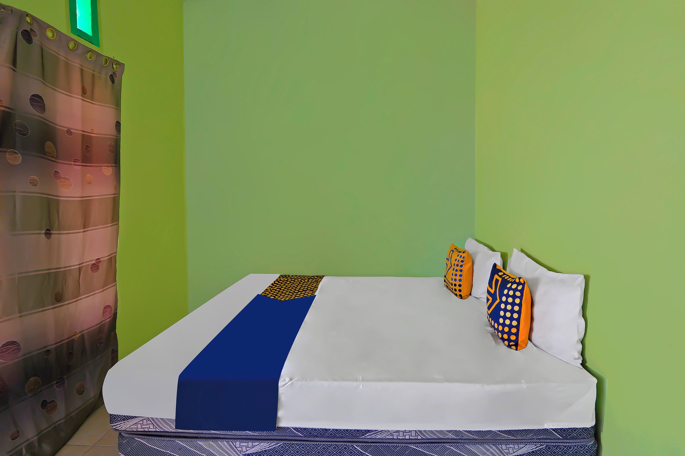 A bed with white bedding, a blue accent, and patterned pillows.