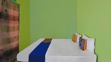 A bed with white bedding, a blue accent, and patterned pillows.