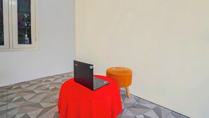 Une pièce avec une table rouge, un ordinateur portable et un tabouret orange.