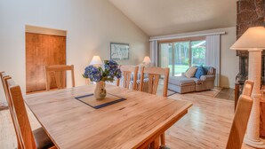 A dining area with a wooden table and chairs, a vase with flowers, and a sofa with striped cushions. - Pet Friendly, Single Level Condo Across from Clubhouse (Sunriver)