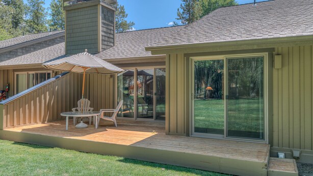 A modern house with a deck, outdoor seating, and large sliding glass doors. - Pet Friendly, Single Level Condo Across from Clubhouse (Sunriver)