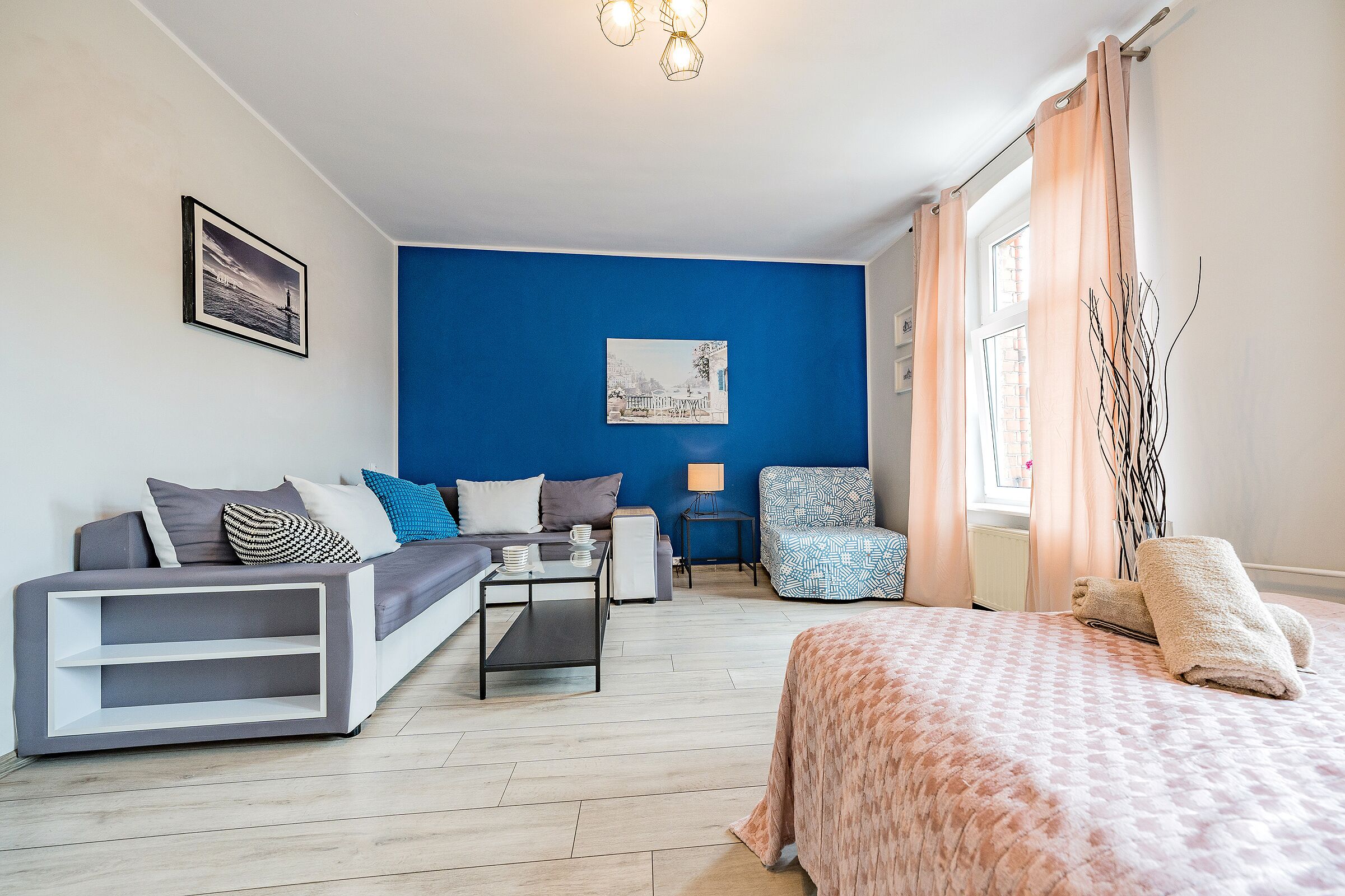 A modern bedroom with a bed, a sofa, a chair, and a small table.
