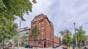 A red brick building with multiple windows and a central entrance. - Apartament Przytulny na Starym Mieście 2 sypialnie (Gdansk)