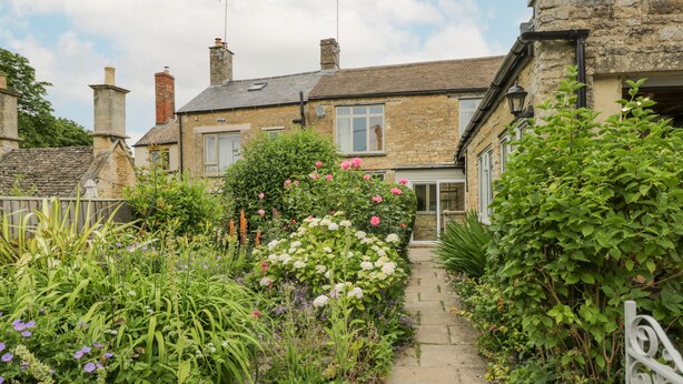 Une maison en pierre avec un chemin de jardin menant à l’entrée.