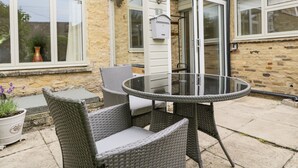 Une terrasse dotée de meubles en osier et d’une table en verre.