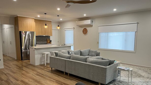 Una cocina moderna con una isla integrada, un sofá modular gris y una pequeña mesa redonda.
