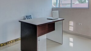 Un espace de bureau moderne avec un bureau en bois foncé, un ordinateur portable et une fenêtre donnant sur des immeubles.