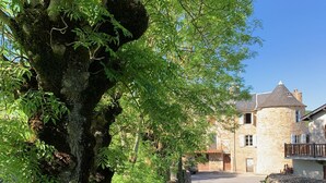 Un bâtiment en pierre, avec un mur en pierre et un arbre devant.