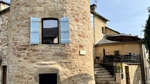 Un bâtiment en pierre doté d’une tour ronde, d’un escalier menant à une zone abritée et d’une enseigne indiquant la présence d’un restaurant.