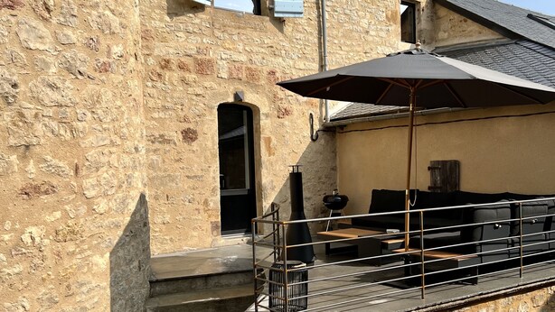 Un bâtiment en pierre doté d’un balcon, de places assises extérieures et d’une cheminée.