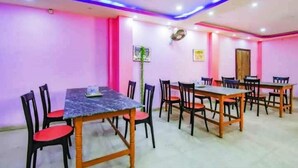 Un salón de conferencias con mesas y sillas, paredes rosas e iluminación LED azul.