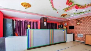 Zona de recepción con diseño moderno, que incluye un mostrador de recepción, una pantalla grande y un muro con diseño.